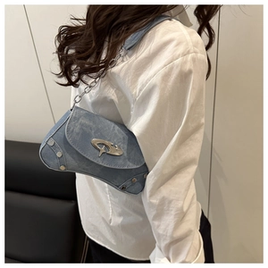 Close-up of light blue denim baguette bag with silver rivets and metal chain strap