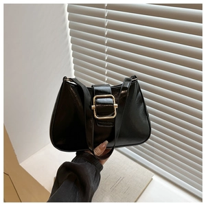 Detail of black glossy PU leather underarm bag featuring a bold gold square metal buckle