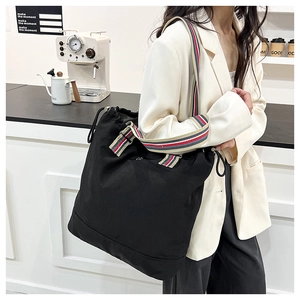 Detailed shot of a black large-capacity canvas tote bag with striped woven shoulder straps