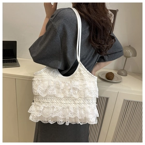 Dettaglio della borsa tote in pizzo bianco con eleganti volant e spalline sottili in stile