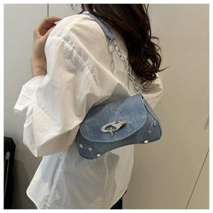 Detail of light blue denim underarm bag with silver cross star buckle and chain strap
