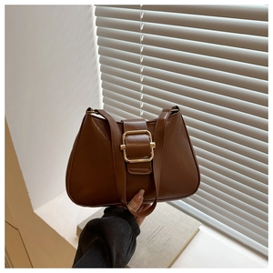Detail of vintage brown leather handbag with large gold square buckle and glossy finish