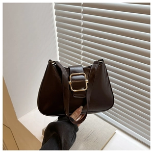 Detail of dark brown retro oil leather texture and gold buckle on the shoulder bag