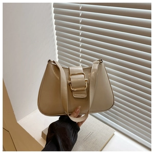 Detail of a beige underarm bag showing the glossy leather texture and golden square buckle