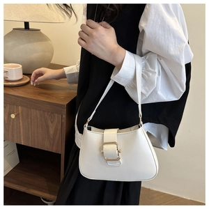 Dettaglio di una borsa a spalla in pelle bianca con fibbia dorata e un design raffinato