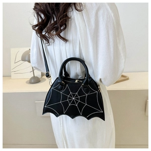 Detail of black spiderweb saddle bag with bat-wing shape shown on woman in white dress