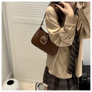 Dettaglio di una borsa a spalla vintage marrone con fibbia dorata su una modella