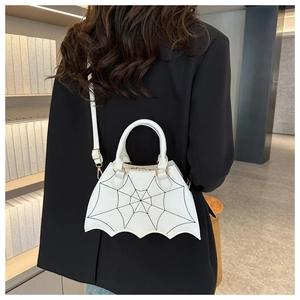 Detail of white PU leather bat-shaped bag featuring black spider web embroidery texture