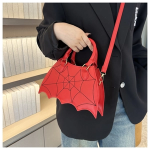 Detail of red bat-shaped saddle bag with black spider web pattern and gold hardware