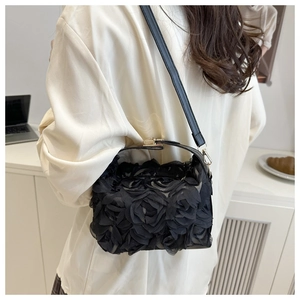 Detail of elegant black shell bag with 3D floral roses and gold metal clasp closure