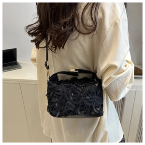 Detail of 3D fabric rose flowers and gold hardware on black elegant crossbody bag