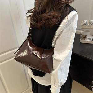 Dark brown minimalist underarm bag with glossy finish and gold metal bar accent