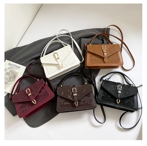 Flat lay of five textured crossbody bags in multiple colors with snakeskin flap detail