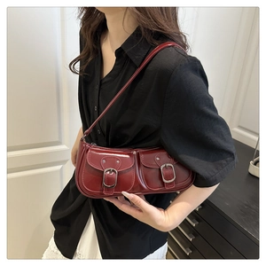 Close-up of wine red glossy leather baguette bag with dual metallic buckle pockets