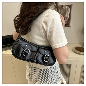 Close-up of black baguette bag featuring dual front pockets and silver metal buckles