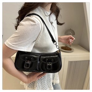 Chic black baguette bag with buckle pockets shown on shoulder in a vintage setting
