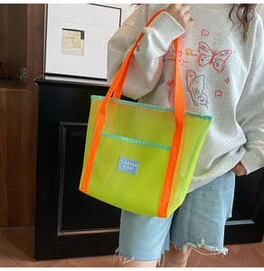 Detail of neon green mesh beach bag with orange handles and blue logo patch