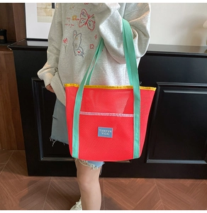 Detail of red mesh tote bag with mint green straps and contrast yellow piping detail