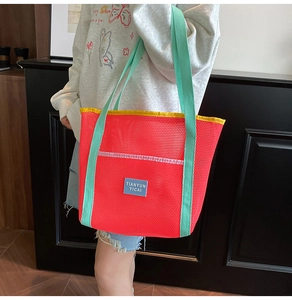 Close-up of red mesh beach bag with green straps and yellow trim highlighting the texture