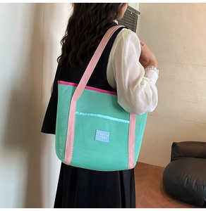 Close-up of mint green mesh beach tote with pink straps and brand logo on the front