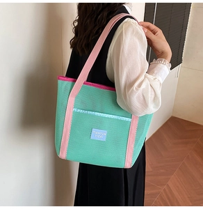 Detail of green mesh beach bag with pink straps and a blue front pocket for summer travel