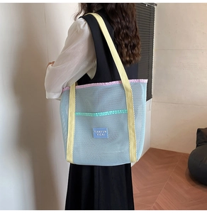 Close-up of mesh beach bag showing light blue fabric and bright yellow shoulder straps