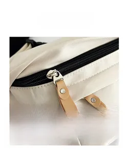 Macro detail of dual metal zippers with leather pullers on ivory canvas saddle bag