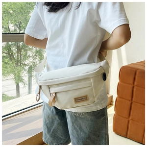 Detail showing high-quality waterproof nylon fabric and leather logo patch on the crossbody bag