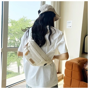 Model wearing a cream-colored waterproof nylon crossbody bag in a casual lifestyle setting