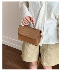 Details von gewebtem Stoff und glattem braunem Leder an der schicken Handtasche
