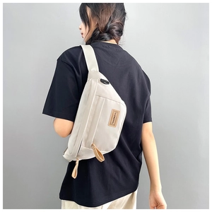 Detail of off-white nylon saddle bag showing the leather logo patch and zip puller