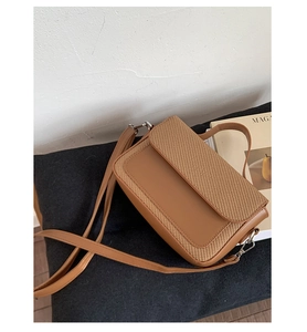 Detail view of contrast color handbag with silver metal clasp and detachable shoulder strap