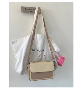 Detail of crossbody bag with beige woven texture, brown leather trim, and plush coin purse