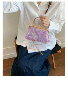 Detail of purple 3D floral petals on a classic kiss-lock bag with gold metal handle