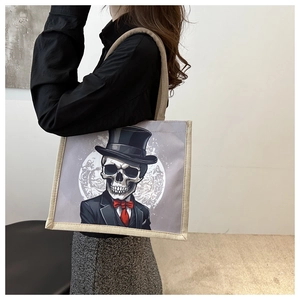 Detail of canvas tote bag featuring a gothic skull in a suit and wooden woven handles