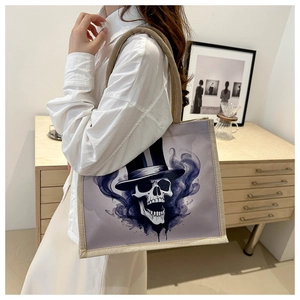 Detail of canvas tote bag with skull print and rope handle on a model shoulder