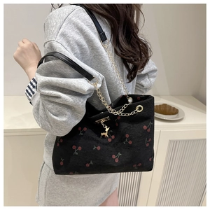 Detailansicht der schwarzen Kordtasche mit Kirschprint und goldenem Hirschanhänger