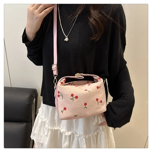 Detail of pink woven small square bag featuring sweet cherry patterns and metal clasp