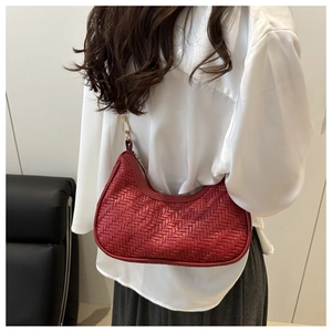 Dettaglio della borsa a spalla rossa intrecciata con finiture dorate e design hobo