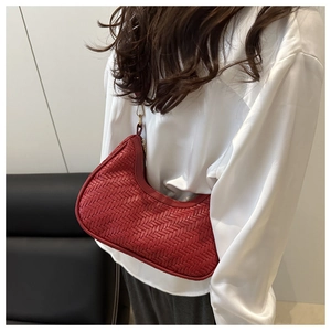 Dettaglio della borsa hobo rossa in pelle intrecciata con zip dorata indossata da modella