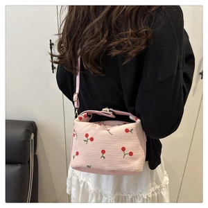 Detail of pink corduroy handbag with cherry print and adjustable metal buckle