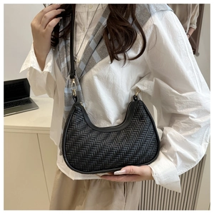 Close-up of black woven crescent underarm bag with golden zipper and leather strap