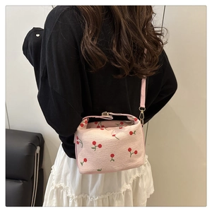 Dettaglio della borsa a secchiello in velluto rosa con ricami ciliegia e chiusura in metallo