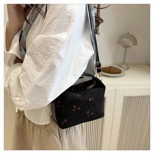 Detail of black canvas tote bag with red cherry print and adjustable shoulder strap