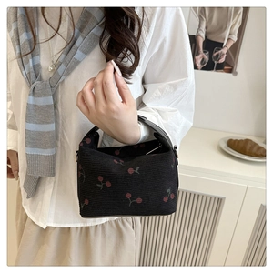 Detail of sweet cherry print handbag with black knit texture and leather handle