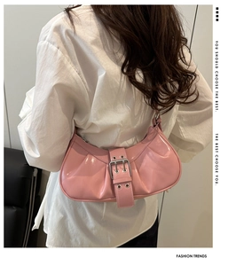 Detail of pink patent leather moon bag featuring a stylish buckle strap on a white shirt