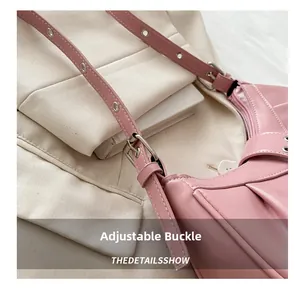 Detail of adjustable silver buckle on pink crescent leather shoulder bag with folds