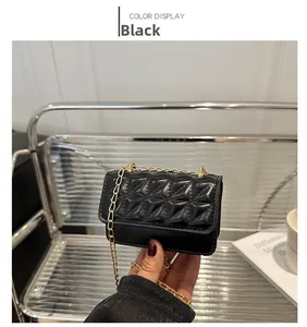 Detail of black quilted leather mini crossbody bag with golden chain strap