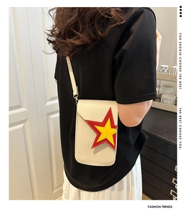 Modèle portant un petit sac bandoulière beige brodé d'étoiles dans un cadre chic
