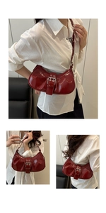 Detail view of dark red patent leather shoulder bag with metallic buckle and retro finish